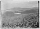  Orville making right turn, showing warping of wings, hill visible in front of him; Kitty Hawk, North Carolina 
