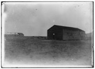  View of the camp building at Kitty Hawk from the northwest, showing the old building to the left and the newly constructed building on the right, with a window on its east side and outside wall braces visible on its west side. 


