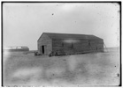  View of the camp building at Kitty Hawk from the northwest, showing the old building to the left and the newly constructed building on the right, with a window on its east side and outside wall braces visible on its west side. 

