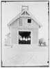  Kill Devil Hills Lifesaving Station, with four crew members wearing white hats and jackets standing in doorway, and a boat near outer wall at right; Kitty Hawk, North Carolina.