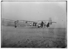  Glider being prepared for flight by Orville and assistants; a number of reporters stand off to the right. 

