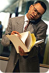 A man talking on the phone while looking through some paperwork.