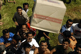 Villagers in a small town on the island of Sumatra, Indonesia, catch boxes of food dropped from a helicopter.  U.S. Navy photo by Photographer's Mate Airman Nicholas B. Morton.