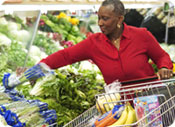 A woman shopping for vegetables in a grocery store.