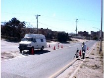 Photo of van near side of road with a man on the opposite side setting up sensing equipment