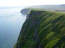 View from the top of the high rocky cliffs of High Bluffs, with birds and the Bering Sea in the background