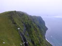 Sea birds fly in front of the cliffs of High Bluffs on St. George Island, and the Bering Sea is visible at the foot of the cliffs