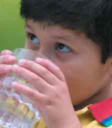 A boy is drinking a glass of water.