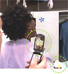 A woman using her credit card at a store; a person taking a picture with a cel phone of her credit card.