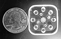 acrylic miniature GEMBE chemical separation device next to quarter for scale