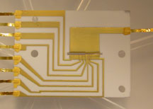 Teleportation takes place inside an ion trap made of gold electrodes deposited onto alumina. The trap area is the horizontal opening near the center of the image.