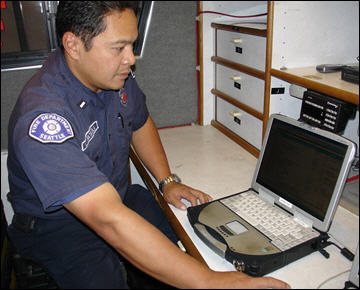 A firefighter works with CAMEO on a laptop in the department hazmat vehicle.