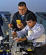Two researchers set up metallurgy research instrument.-Copyright Robert Rathe