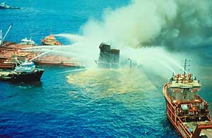 Several ships spraying water on a smoking vessel, the T/V Mega Borg.