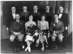 Amelia Earhart seated with seven other people, including Carl Spaatz and military officers