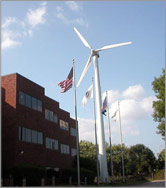 Photo of wind turbine in front of office building.
