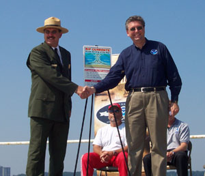 Barry Sullivan, National Park Service general superintendent, Gateway National Recreation Area, N.J.,(left)and Gary Szatkowski, meteorologist-in-charge of the National Weather Service forecast office in Mount Holly, N.J. (right), unveil the new Rip Current Awareness sign. The sign provides rip current safety information, and depicts the new partnership between the NWS and NPS to promote awareness and safety. 