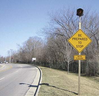 Advance warning signs with flashers, coordinated with traffic signal operation, are common in at least 14 States. An example from Naperville, IL, is pictured here.