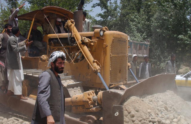 Photograph of Afghan men with a bulldozer scooping up dirt.