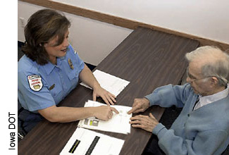 Declines in the working memory capacity of older people can affect memory of critical navigation information provided in signs. This change can be addressed in part through redundant street signs. Here, an older man is being tested by an Iowa driver licensing official.