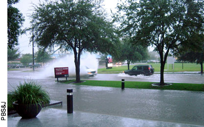 Here, during a rainstorm, a sport utility vehicle and truck are plowing through rainwater as high as the top of the vehicles' tires.