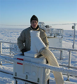 A researcher checks the GVR antennae on a cold, crisp day at the ACRF site in Barrow, Alaska. The radiometer is inside the insulated box beneath the antenna; the data is collected and displayed on the computer inside the instrument shelter.