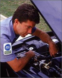 Photo of a mechanic looking under the hood of a car.