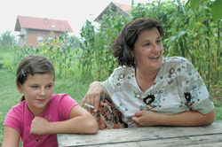 Enisa Hamulic and her 12-year-old daughter Erma sit outside of the home her husband rebuilt in Prijedor, Bosnia.