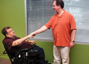 man in a wheelchair and man standing shaking hands