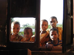 Photo of young boys looking through a school window in Jimma, Ethiopia to observe their peers participating in a "Youth Action Kit" HIV/AIDS prevention activity.