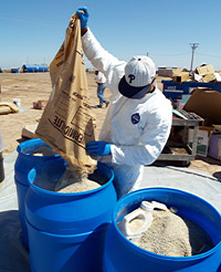 Pouring vermiculite into a barrel of bottled pesticides