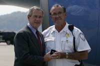President George W. Bush presented the President’s Volunteer Service Award to Joe Dailey upon arrival at the airport in Charleston, West Virginia, on Wednesday, July 26, 2006.  Dailey has been a volunteer for three years with the Charleston Police Department.  To thank them for making a difference in the lives of others, President Bush honors a local volunteer, called a USA Freedom Corps greeter, when he travels throughout the United States.  President Bush has met with more than 500 individuals around the country, like Dailey, since March 2002.