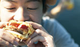 Photo: Asian man eating a fastfood burger