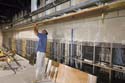 A millworker installs wood finishing trim to a ceiling soffit inside the South Orientation Theater