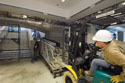 A worker positions an escalator truss into place within the East Front transition zone