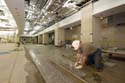 A stone mason lays tile in the Food Service servery area