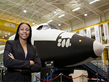 A woman stands in front of a shuttle simulator
