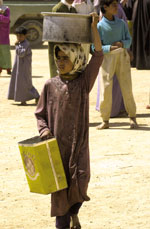 Iraqi girl carries humanitarian aid from a distribution point. [Source: US Department of Defense]