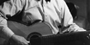 black and white photo of Carl Sandburg playing one of his many guitars