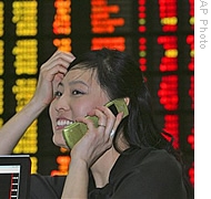 An employee at the Korea Stock Exchange Market smiles in front of an electronic stock board in Seoul, South Korea, 19 Sep 2008