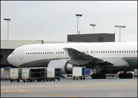 Image of passenger airplane at gate with baggage carts