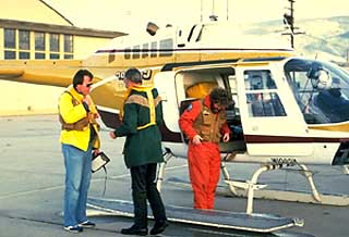 Three men standing in front of helicopter