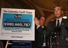 Gutierrez at microphone gesturing toward poster that shows Colombia Tariff Ticker.