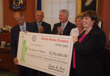 Officials pose with presentation check.  Pictured are Governor John E. Baldacci; Director of the Office of Business Development for the Maine Department of Economic and Community Development (DECD) James Nimon; DECD Commissioner John Richardson; Ginnie Ricker from the Maine Emergency Management Agency; Director of Public Affairs Kelly O’Brien. Click for larger image.