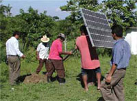 Photo of five men installing a solar energy system. They have a pole with photovoltaic panels
                      mounted on top. Inserting the pole into the ground and fixing it in place.