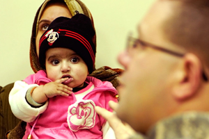 A baby girl watches as Maj. Jason Davis, battalion surgeon for 1st Battalion, 21st Stryker Infantry Regiment, 25th Infantry Division, discusses treatment options for her heart defect with her parents at a public health clinic in the village of Nasr Wa Salam, west of Baghdad. (U.S. Army photo by Sgt. Jerome Bishop)