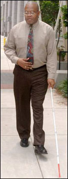 Photo: A visually impaired man walking with a cane.