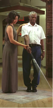 Photo of Woman giving man instruction on use of a cane
