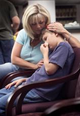 Fotografía de una madre con su hijo que ha sufrido una lesión en la nariz en la sala de espera de un doctor
