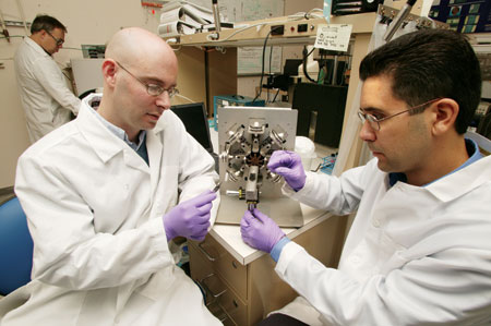 Thomas Wilson, Ward Small, and Jason Ortega prepare a shape-memory foam plug for the crimping machine in their labortory.